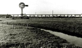 ca. 1952 Blick vom Burger Feld über den Helmschen Bach auf einen Windrotor und auf die Eisenbahn Hochbrücke Hochdonn