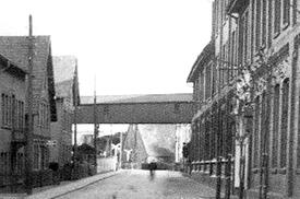 1941 Rumflether Straße mit der sie überspannenden Transportbrücke der Futtermittelwerke Günther & Co. in der Stadt Wilster