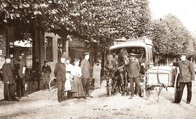 1909 Wewelsfleth - Deichreihe mit dem Postamt, davor Postbedienstete mit Kutsche und Handkarren