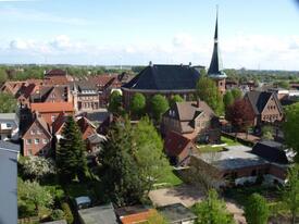 Blick über den Stadtkern von Wilster mit der St. Bartholomäus-Kirche und dem Pastorat hinweg über die Marsch bis zur Elbe